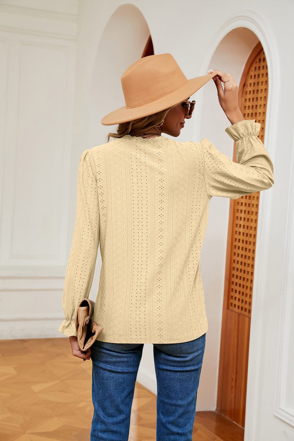 Pastel yellow perforated blouse with ruffle cuffs and eyelet detail.