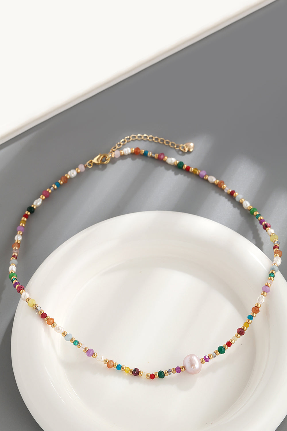 Multicolor beaded gemstone and pearl necklace with gold chain and clasp.