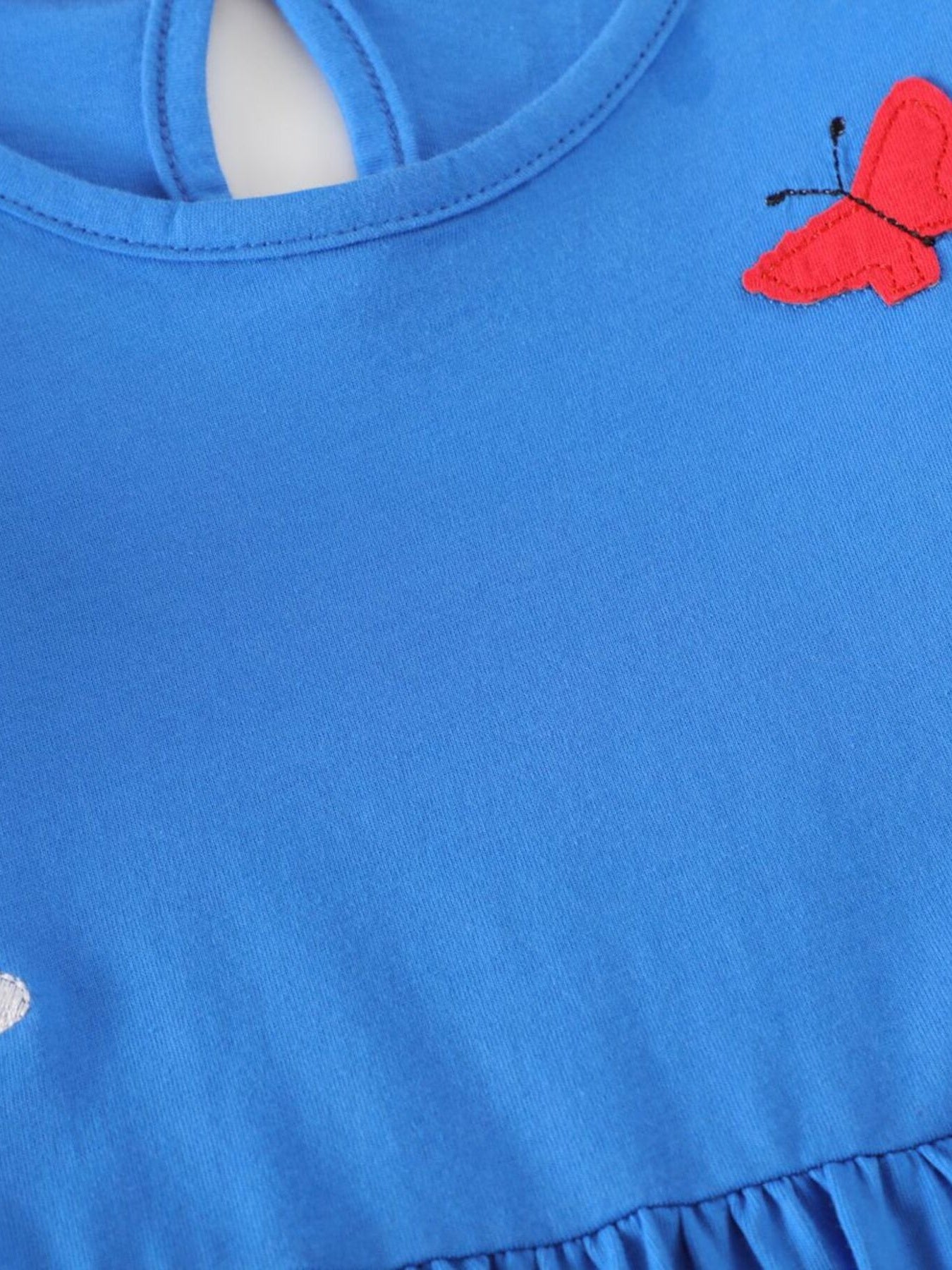 Blue cotton baby dress with red butterfly applique and ruffle hem.