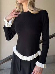 Black knit sweater with contrast white ruffled cuffs and hem