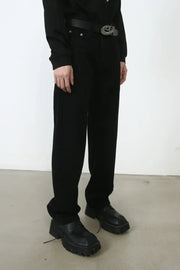 Relaxed fit black denim trousers with a silver buckle belt and chunky shoes.