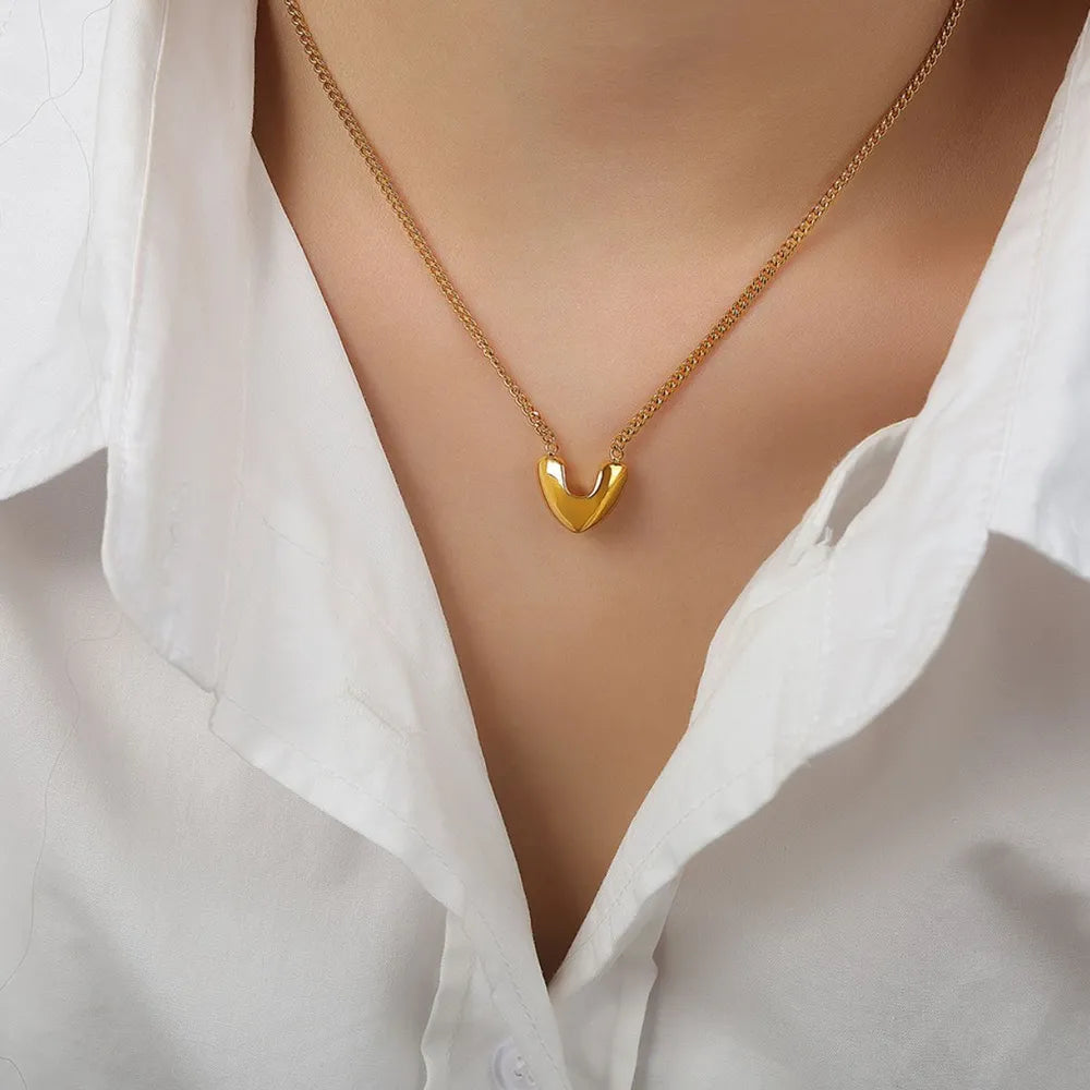 Gold V-shaped pendant necklace on a delicate chain, styled with a white collared shirt.