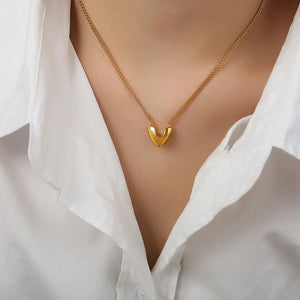 Gold V-shaped pendant necklace on a delicate chain, styled with a white collared shirt.