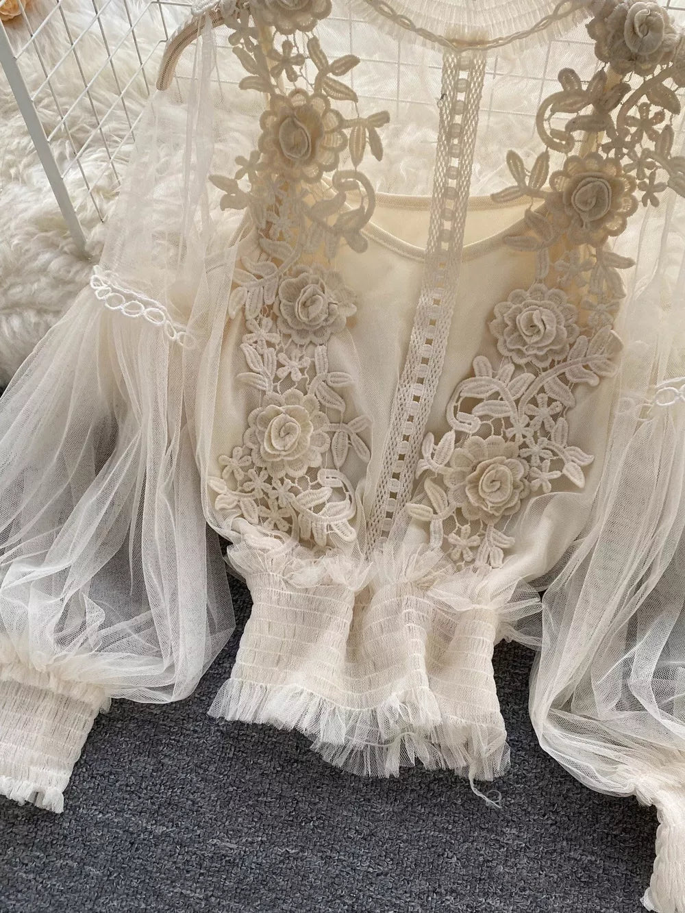 Creamy-white lace blouse with floral embroidery and sheer puff sleeves.