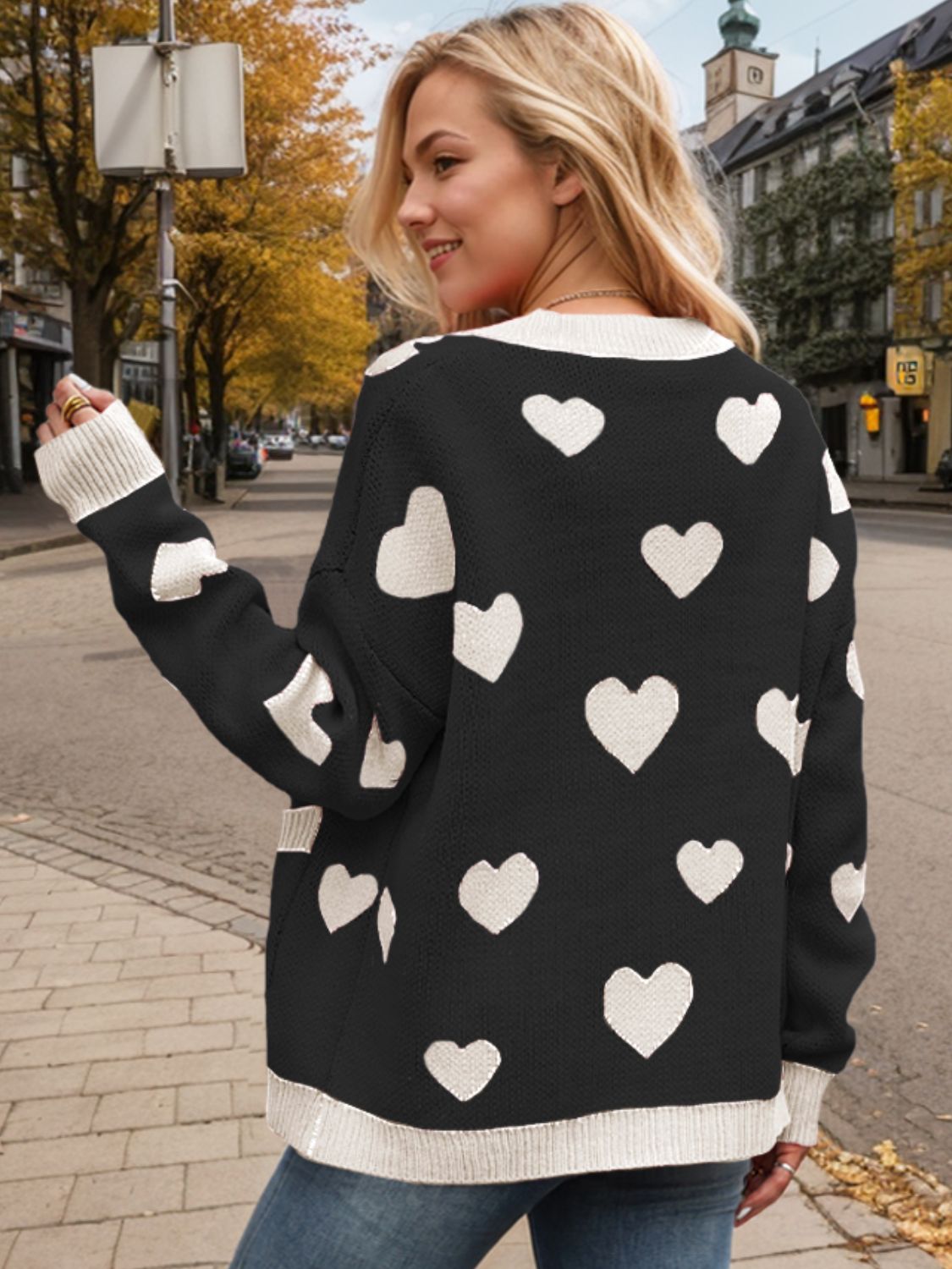 Black intarsia knit cardigan with white hearts, cream trim, and button front.