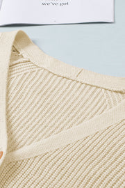 Cream knit cardigan with diamond-cut sleeve detail and ribbed texture.