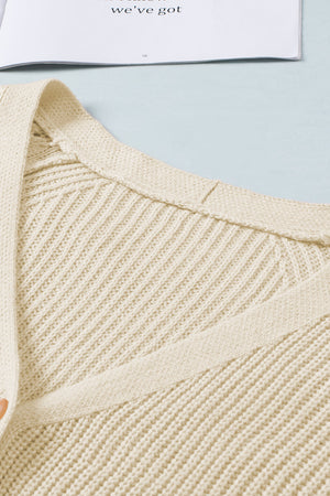 Cream knit cardigan with diamond-cut sleeve detail and ribbed texture.