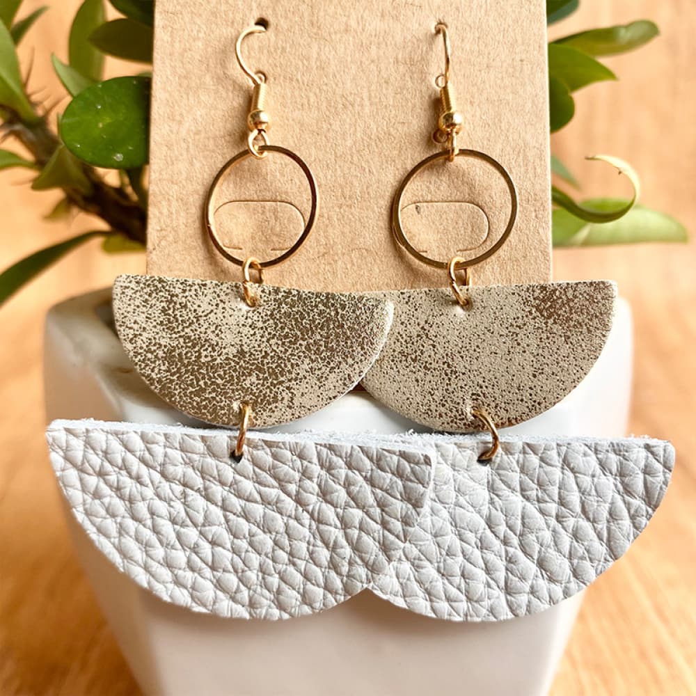 Textured leather half-moon earrings with metallic accents and gold hoops.