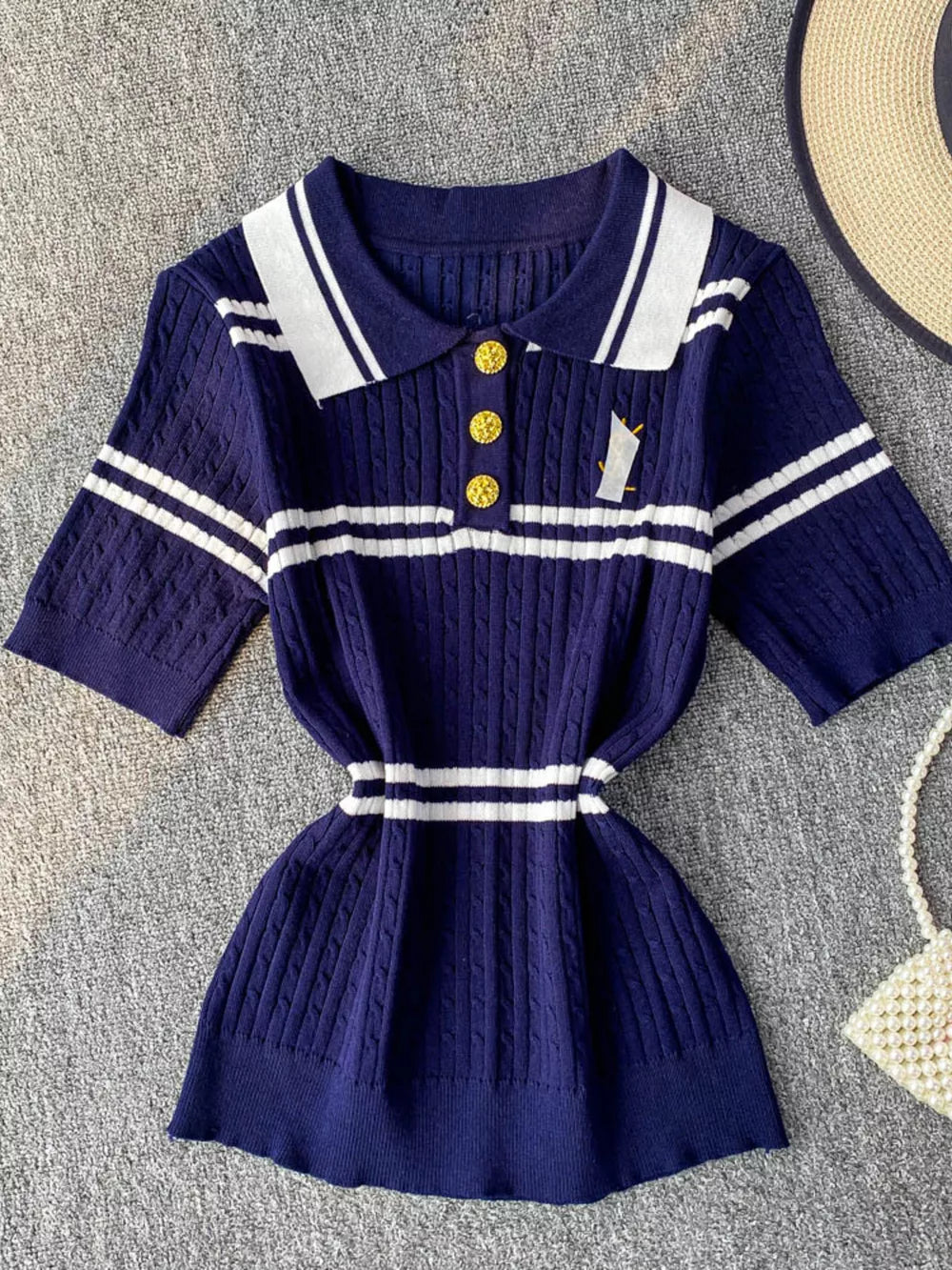 Blue cable knit polo shirt with white stripes and gold buttons.