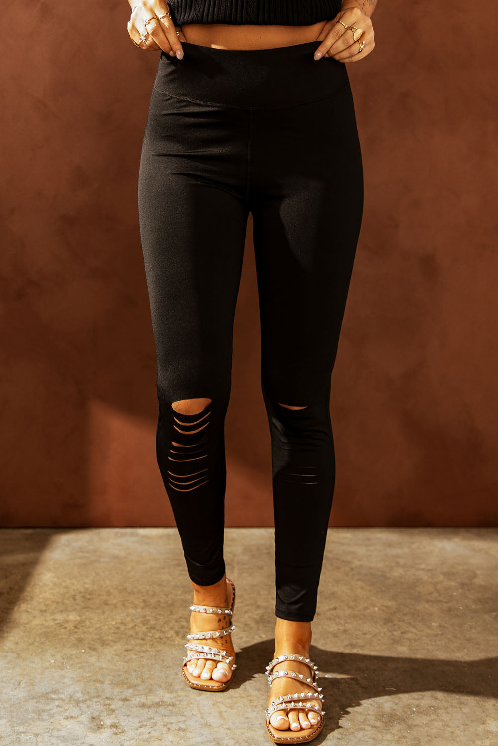 Black performance leggings with distressed knee slits.