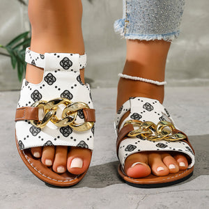 Patterned slide sandals in white with black geometric print and gold chain accent.
