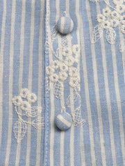 Blue and white striped peplum shirt with white floral embroidery and button details.