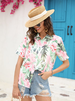 Tropical print camp collar shirt with pink flowers and green leaves, short sleeves, buttoned front.