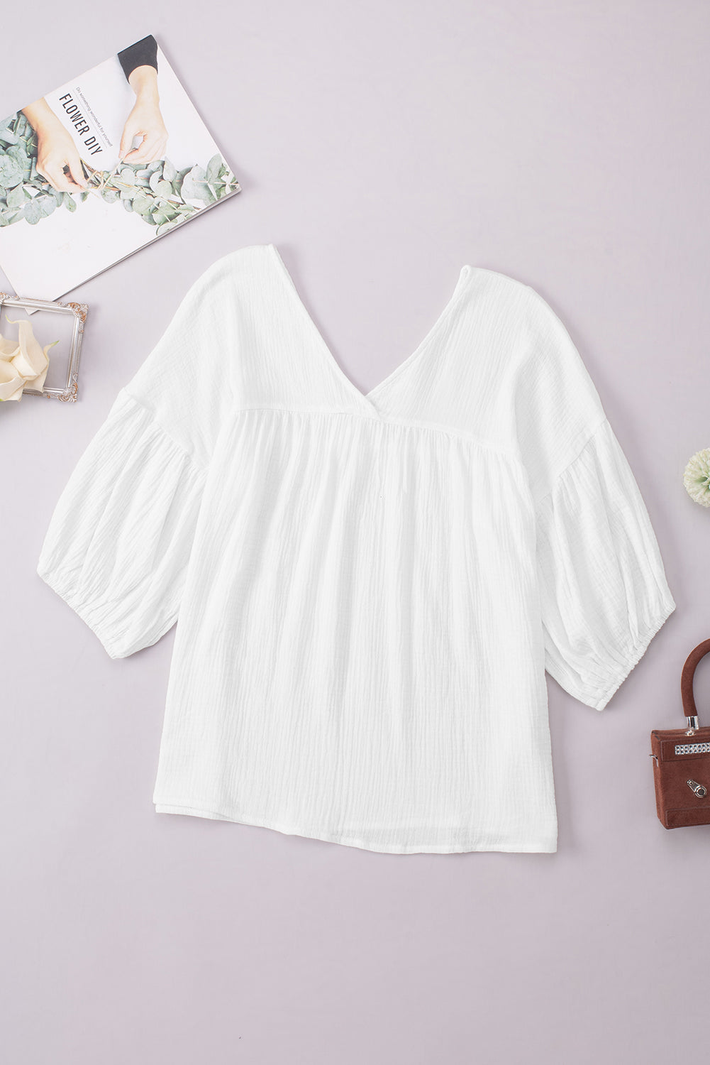 White textured gauze blouse with V-neck and gathered puff sleeves.