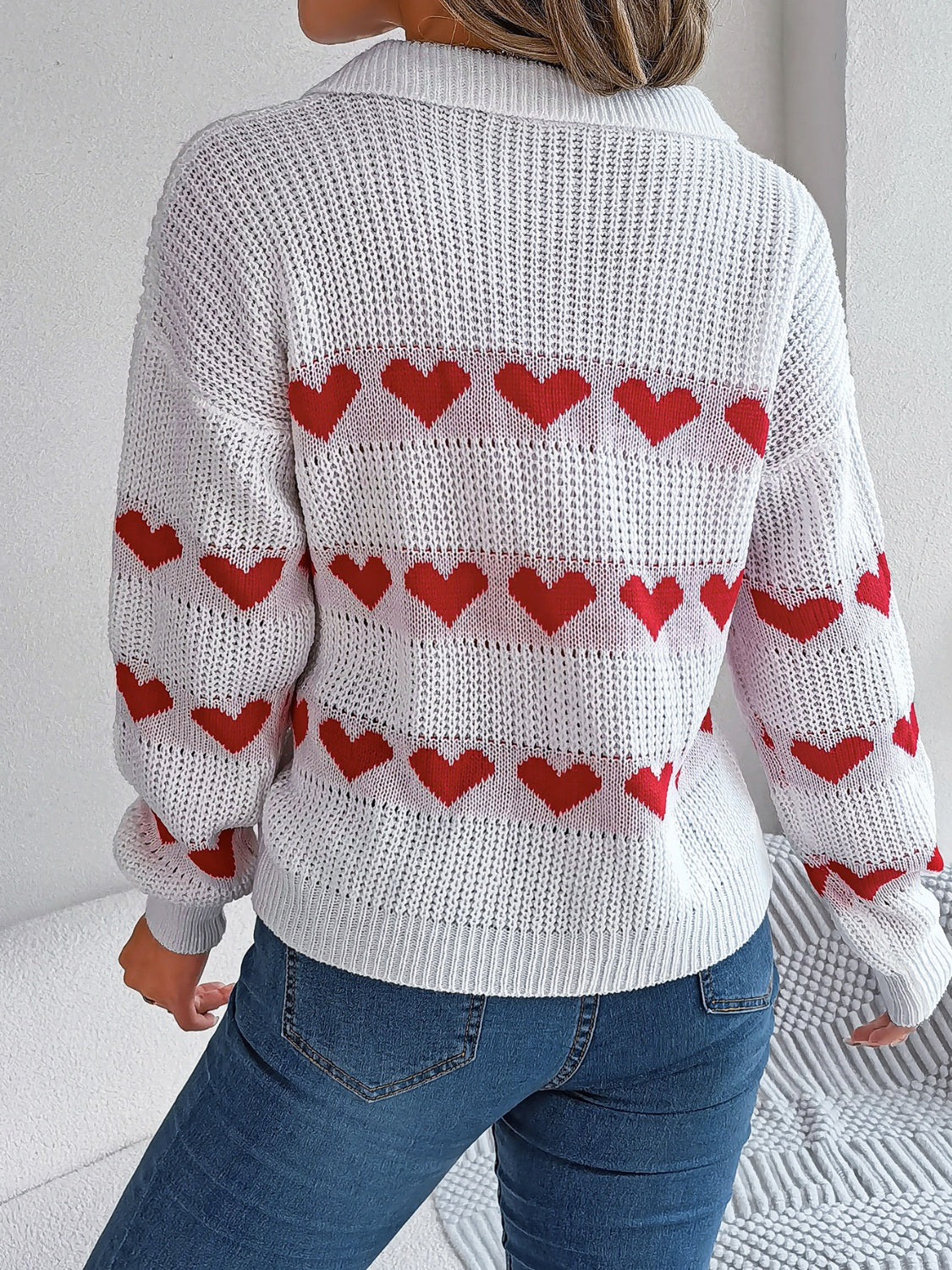White knit polo sweater with red heart stripe pattern and long sleeves.