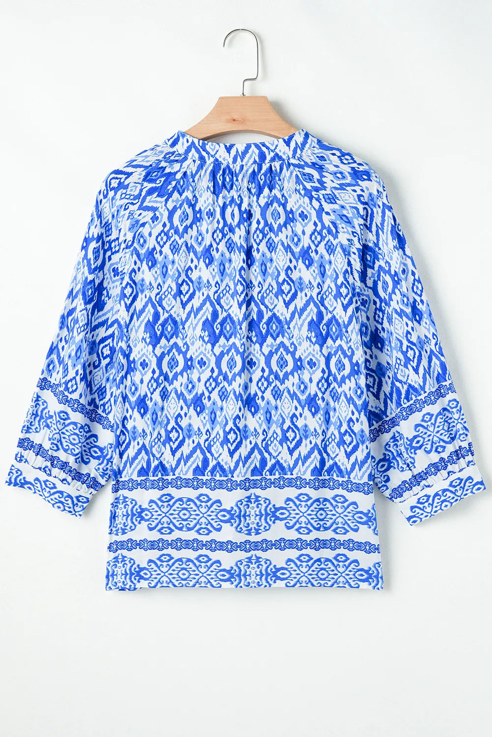 Royal blue ikat print V-neck blouse with border trim and 3/4 sleeves.