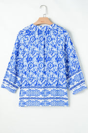 Royal blue ikat print V-neck blouse with border trim and 3/4 sleeves.