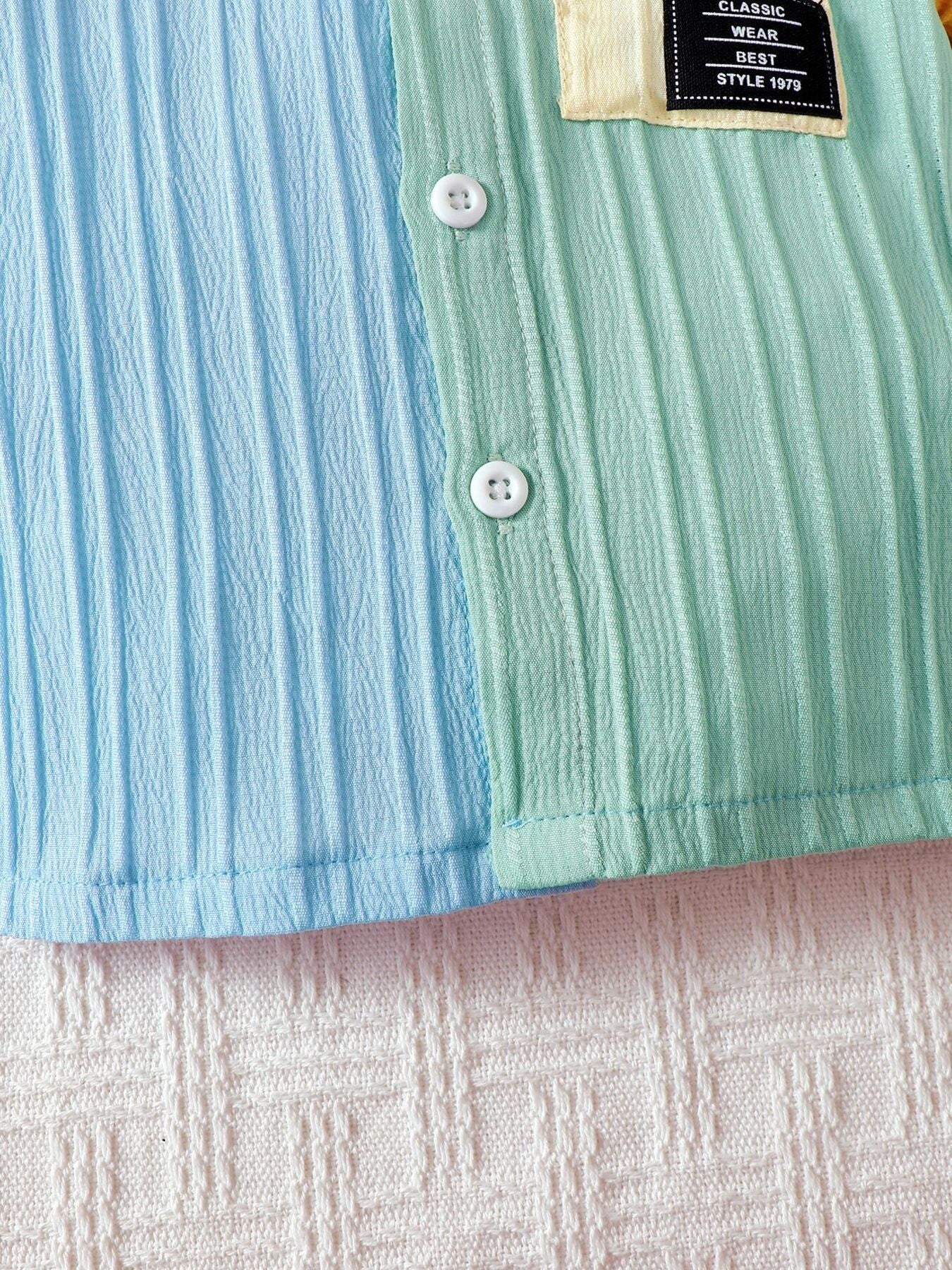 Baby button-down set in blue and green color block with textured fabric and patch detail.