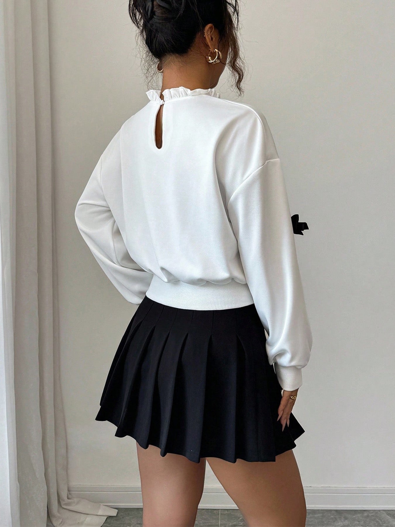 White crew neck sweatshirt with dropped shoulders, ruffled neckline, and keyhole back detail.