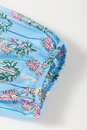 Sky blue floral print smocked yoke blouse with ruffled cuffs and striped accents.