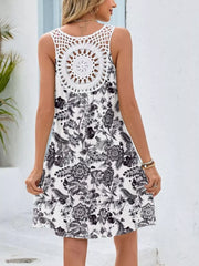 White mini dress with black botanical print and crochet back detail.