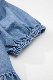 Denim peplum blouse in medium blue with elasticated puff sleeves and ruffled hem detail.