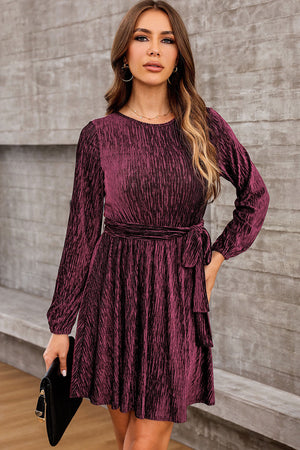 Wine textured pleated mini dress with long sleeves and a tie waist.