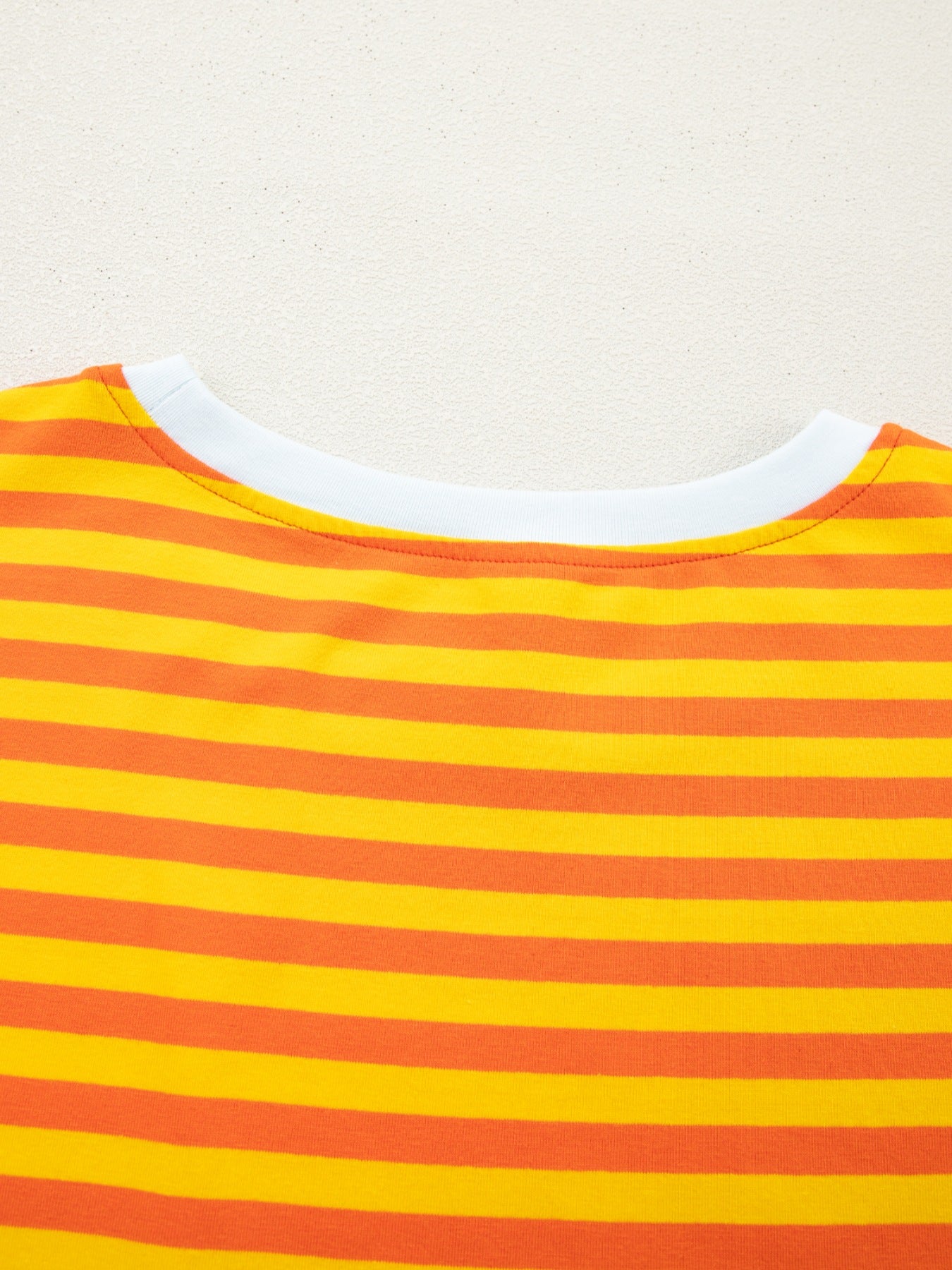 Striped round-neck t-shirt in tangerine and yellow cotton with a white neckline.