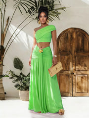One-shoulder ruched crop top and maxi skirt set in bright green with gold floral detail at waist.