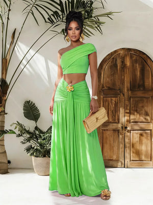 One-shoulder ruched crop top and maxi skirt set in bright green with gold floral detail at waist.
