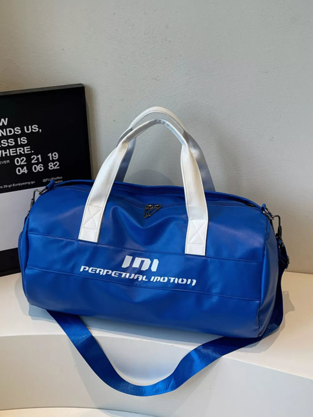 Blue pu leather sporty duffel bag with white handles and bold graphic text.