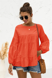 Orange tiered peasant blouse with ruffled bubble sleeves and a round neckline.