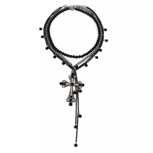 Black layered necklace with beaded strands and a crystal-embellished cross pendant.