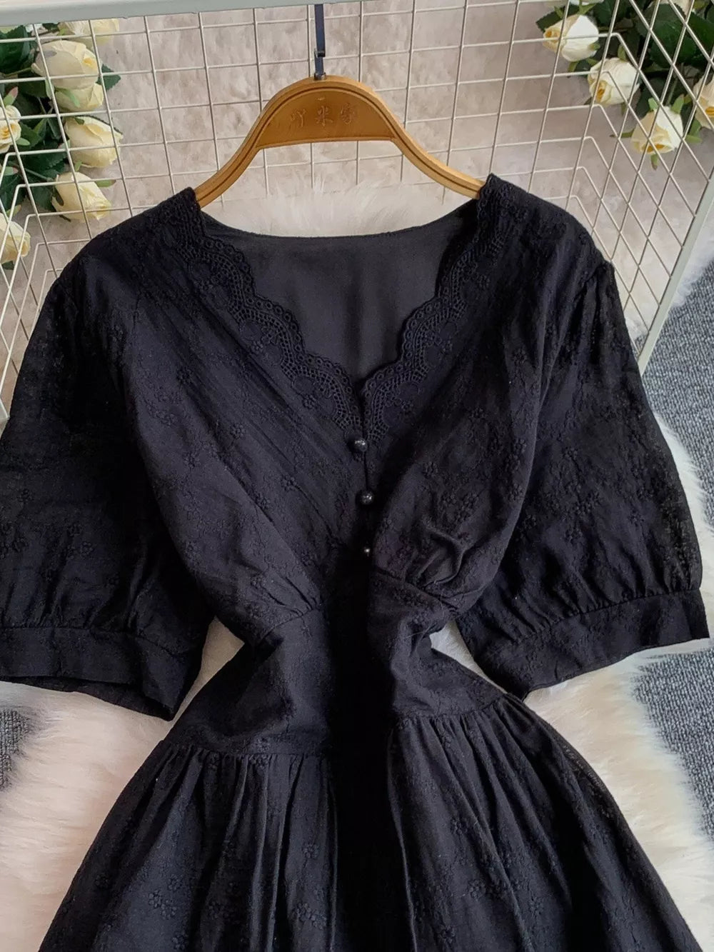 Black lace-embellished A-line midi dress with V-neck and button detail.