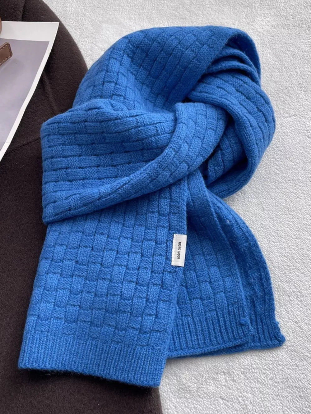 Royal blue wool scarf with basketweave knit pattern and a white 100% wool tag.