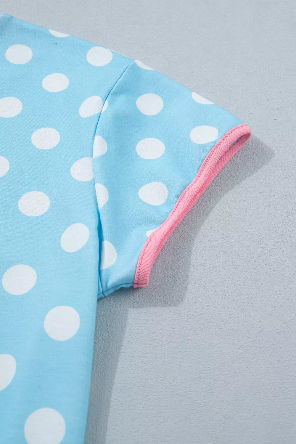 Pastel blue polka dot pajama top with pink trim on sleeve.