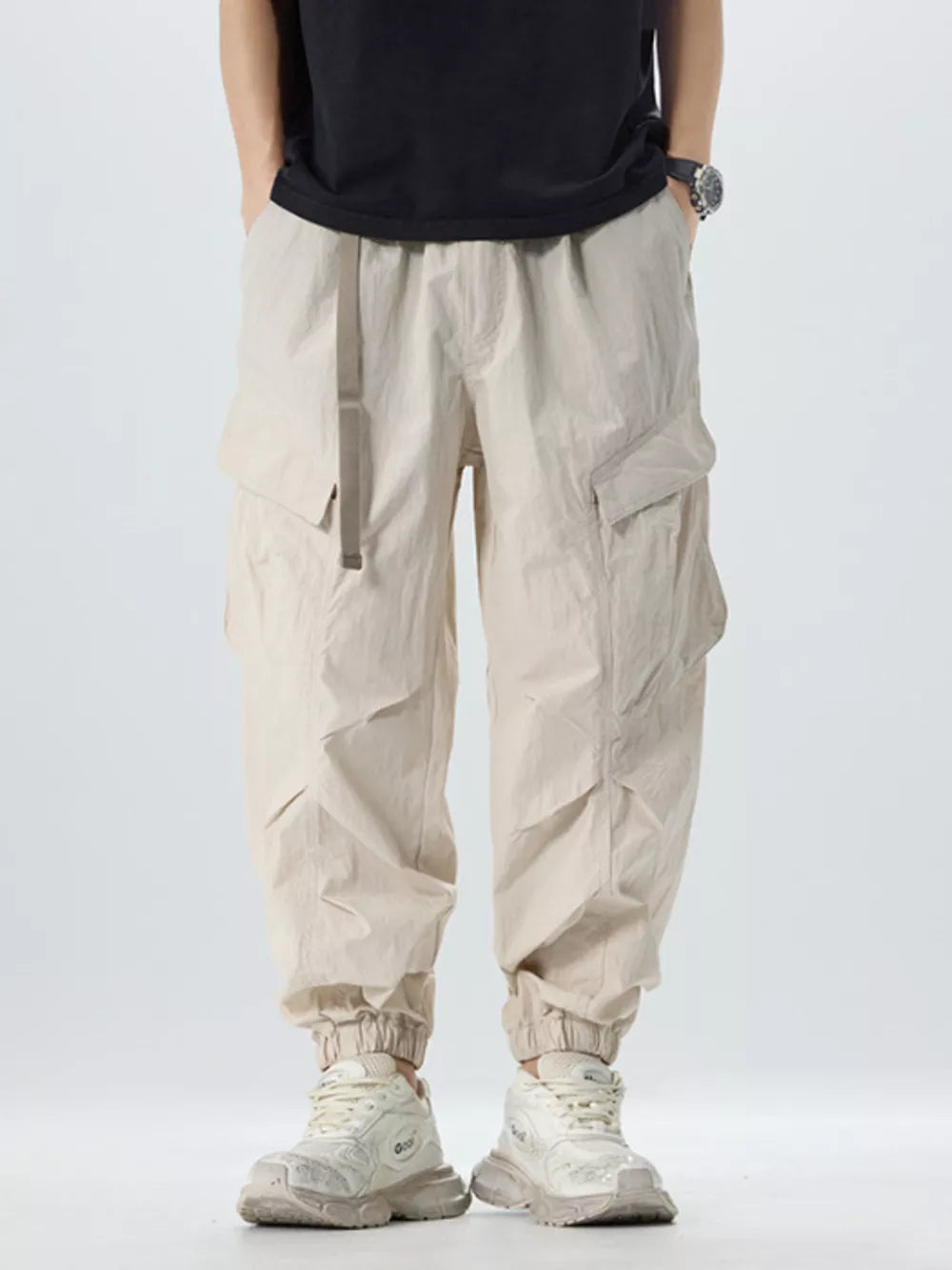 Oversized khaki cargo pants with adjustable belt and cinched ankles.