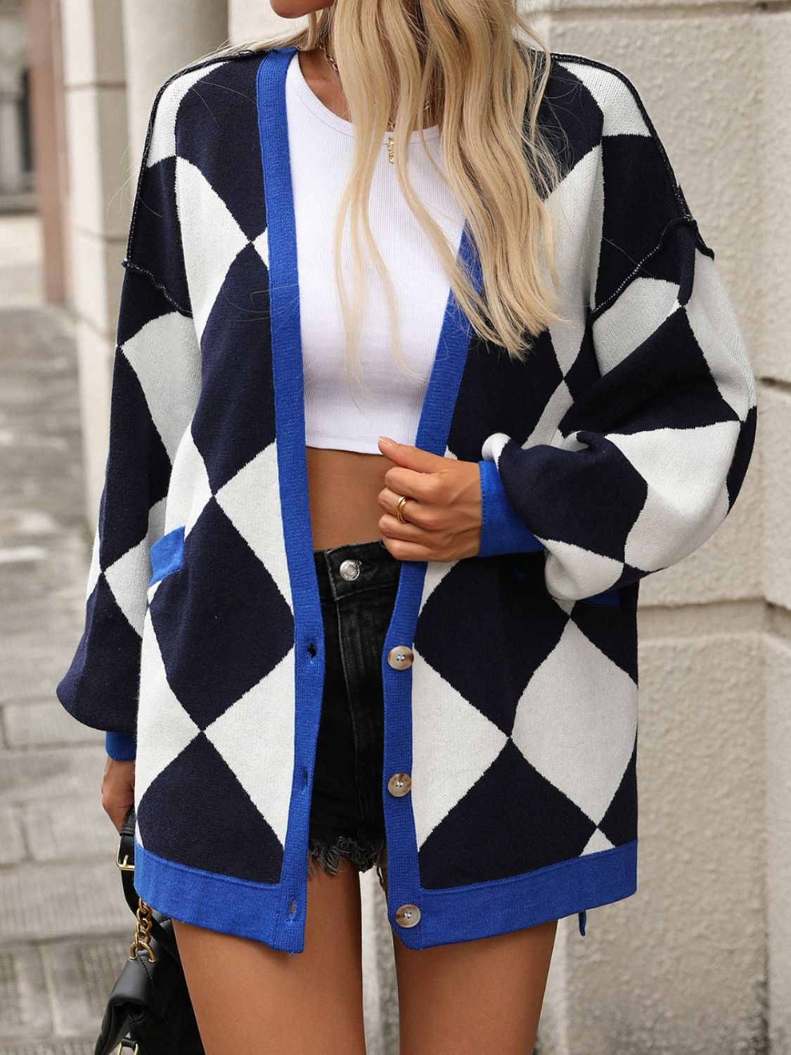 Argyle knit oversized cardigan with pockets in navy and white with blue trim.