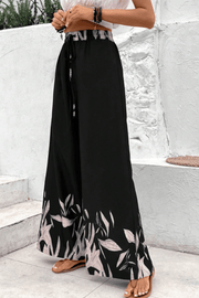 Black wide-leg lounge trousers with botanical print hem and drawstring waist.