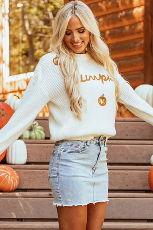 White crewneck sweater with embroidered pumpkin and text detail, acrylic knit.
