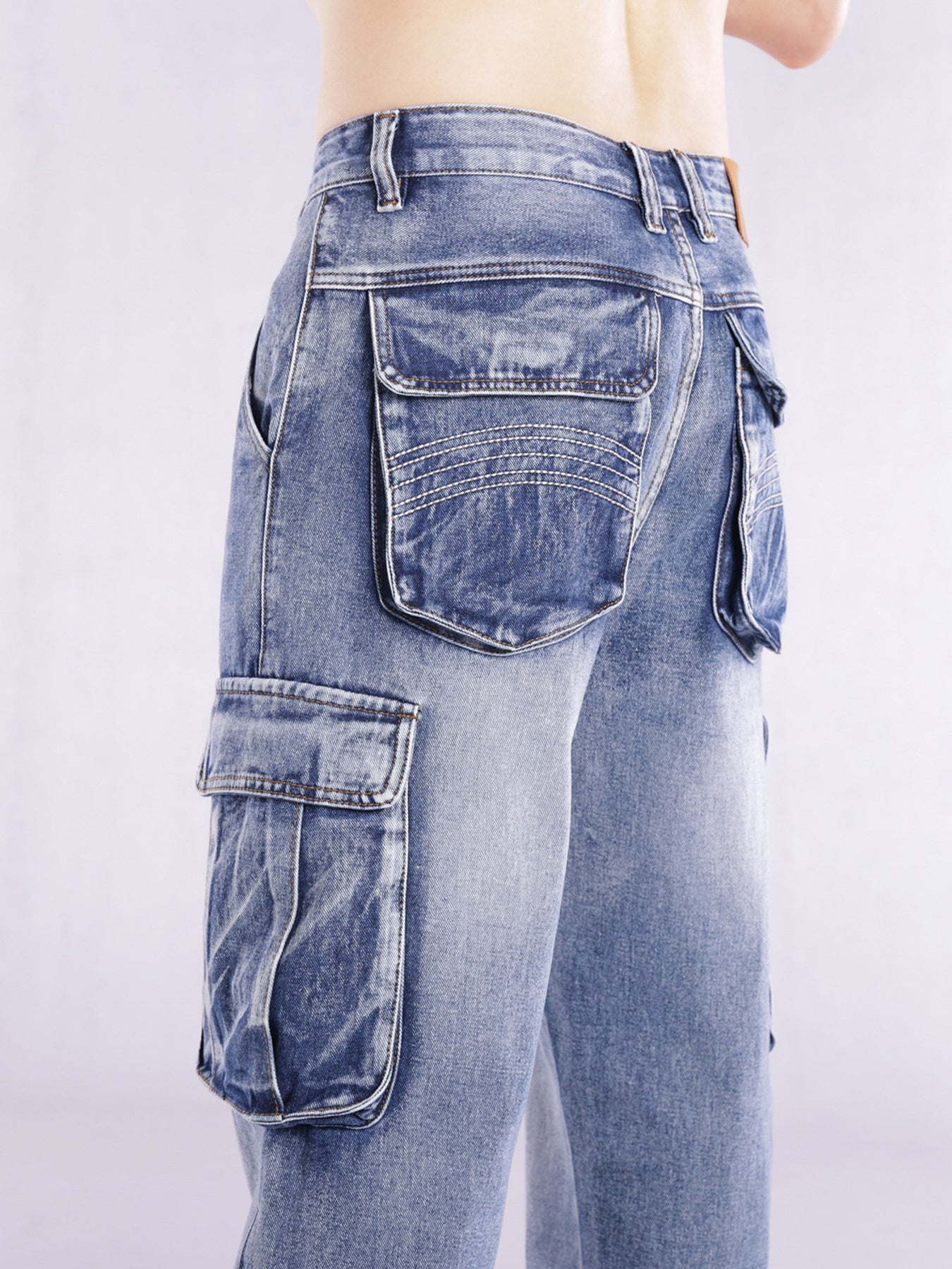 Relaxed fit light wash denim cargo jeans with flap pockets and contrast stitching.