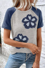 Gray t-shirt with blue raglan sleeves and two denim floral appliques.