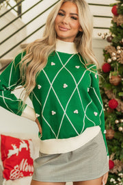 Green argyle knit sweater with white trim and pom-pom embellishments, mock neck.