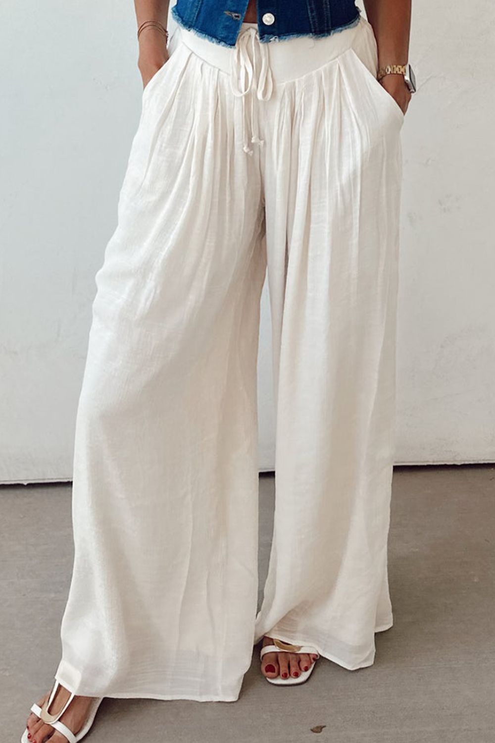 White linen palazzo trousers with pleats and drawstring waist.