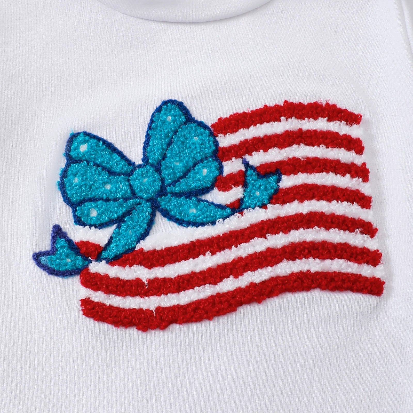 White cotton tee with patriotic applique of red and white striped flag with a blue bow and stars.