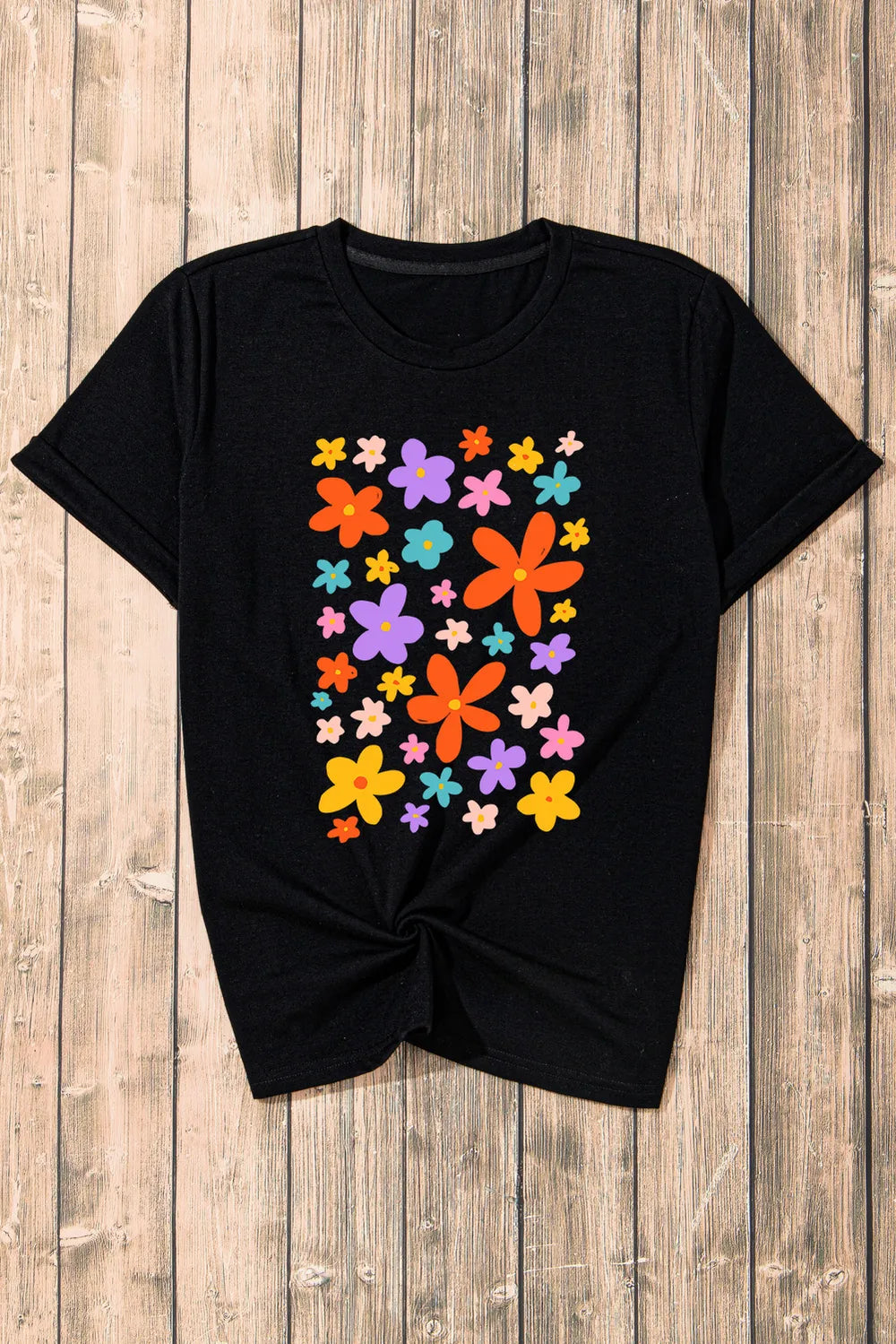 Black round neck tee with a colorful bloom print and twisted hem.