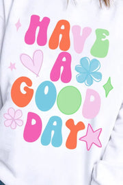 White crewneck sweatshirt with colorful "HAVE A GOOD DAY" graphic and retro stars and flowers.