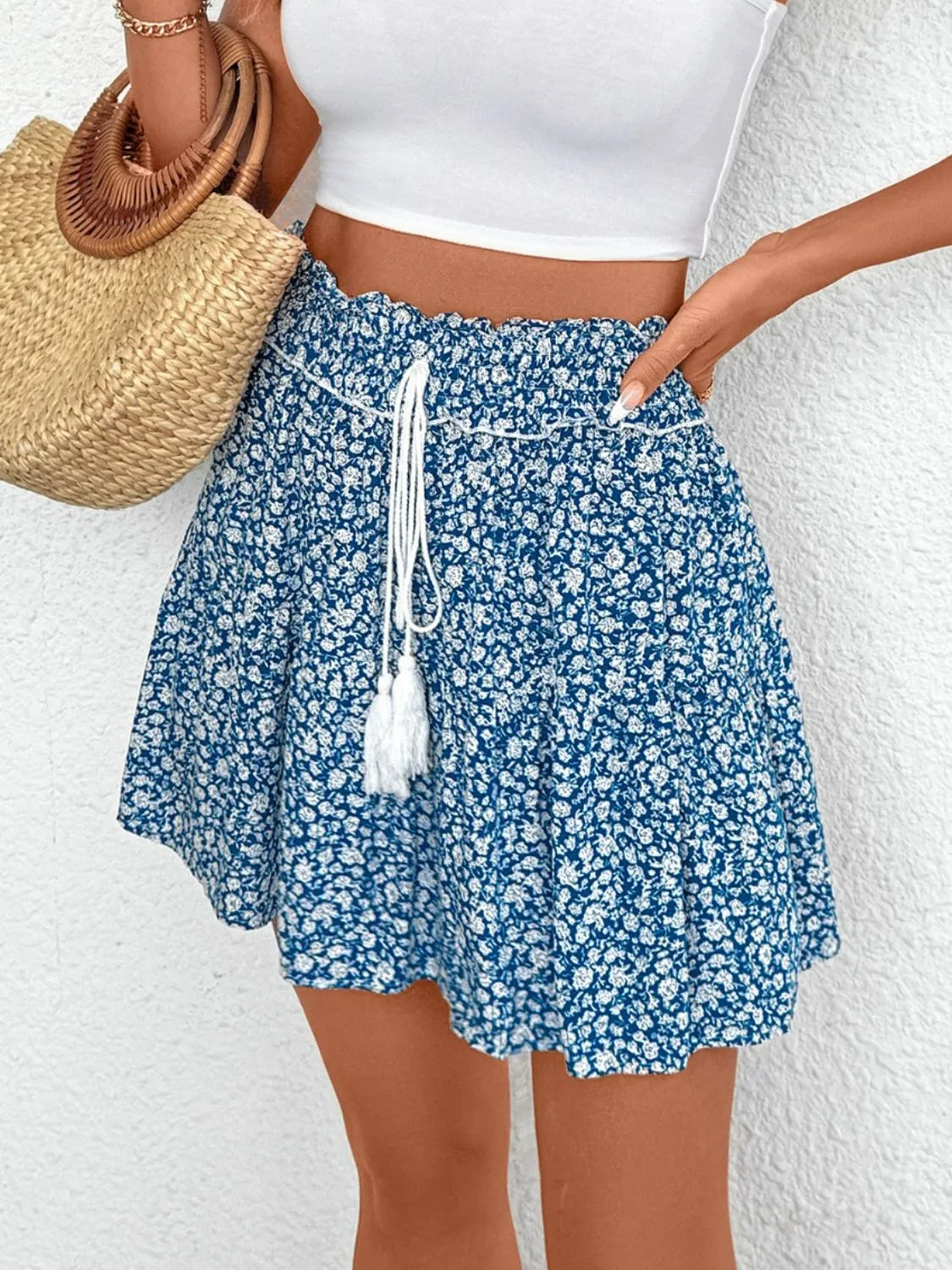 Light blue ditsy floral mini skirt with ruffled hem and drawstring waist with tassels.