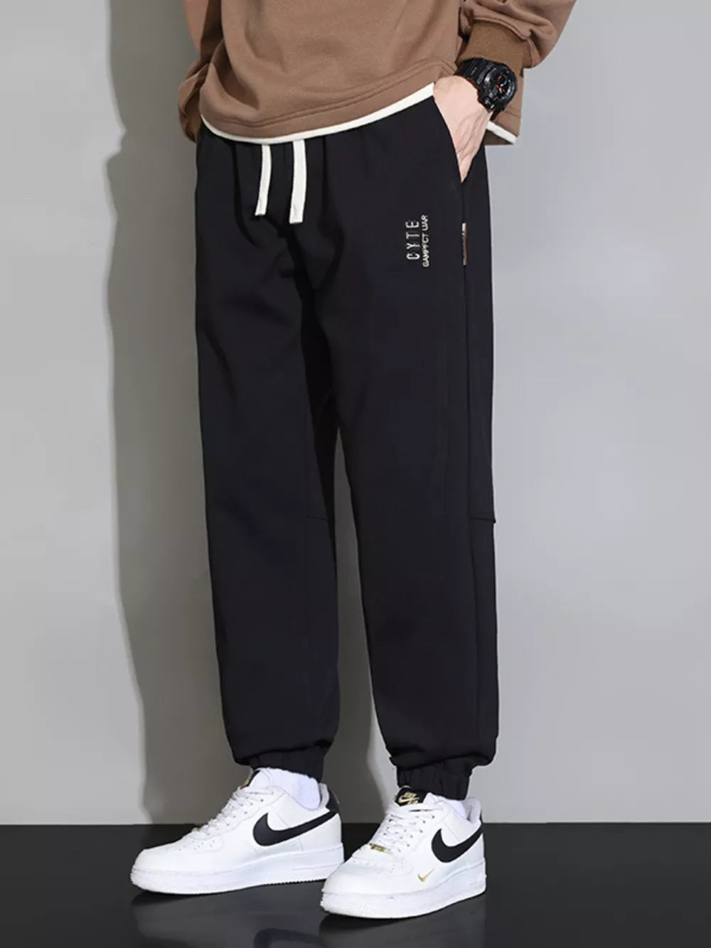 Black cuffed ankle joggers with white drawstring and subtle logo detail.