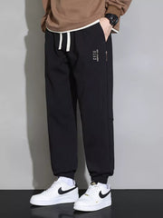 Black cuffed ankle joggers with white drawstring and subtle logo detail.